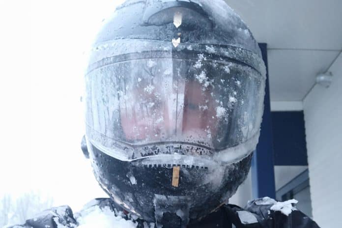 Doorrijden motorrijder met een bevroren motorhelm winter